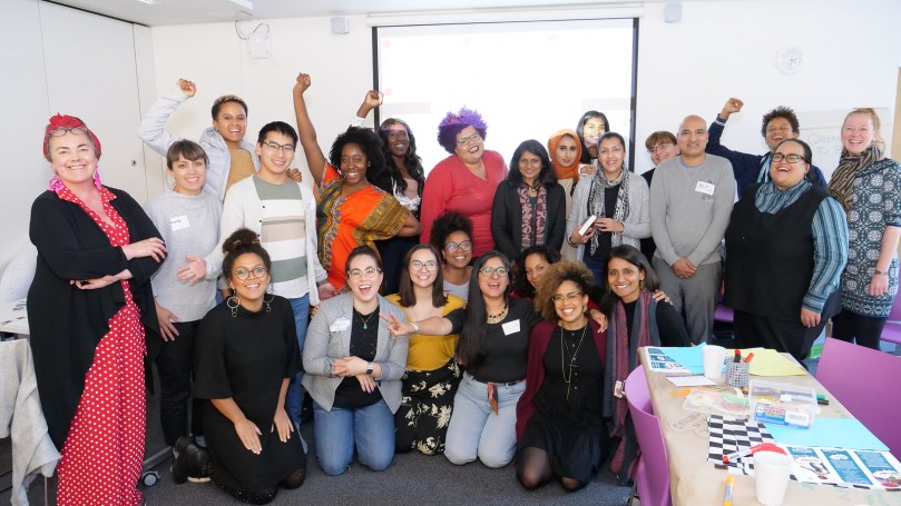 A smiling, happy, racially diverse group of people in colourful clothing